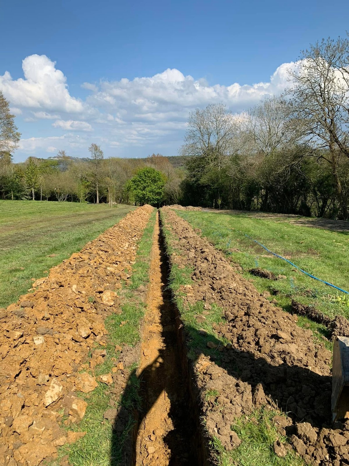 Long excavated service trench running through grassland