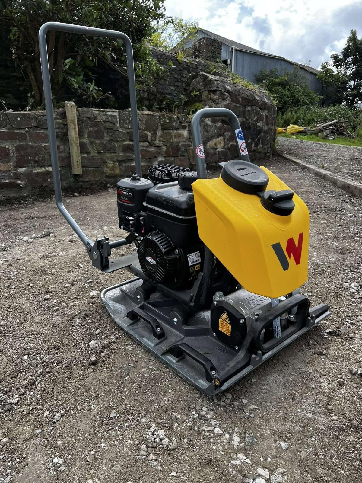 Yellow plate compactor on a prepared gravel surface