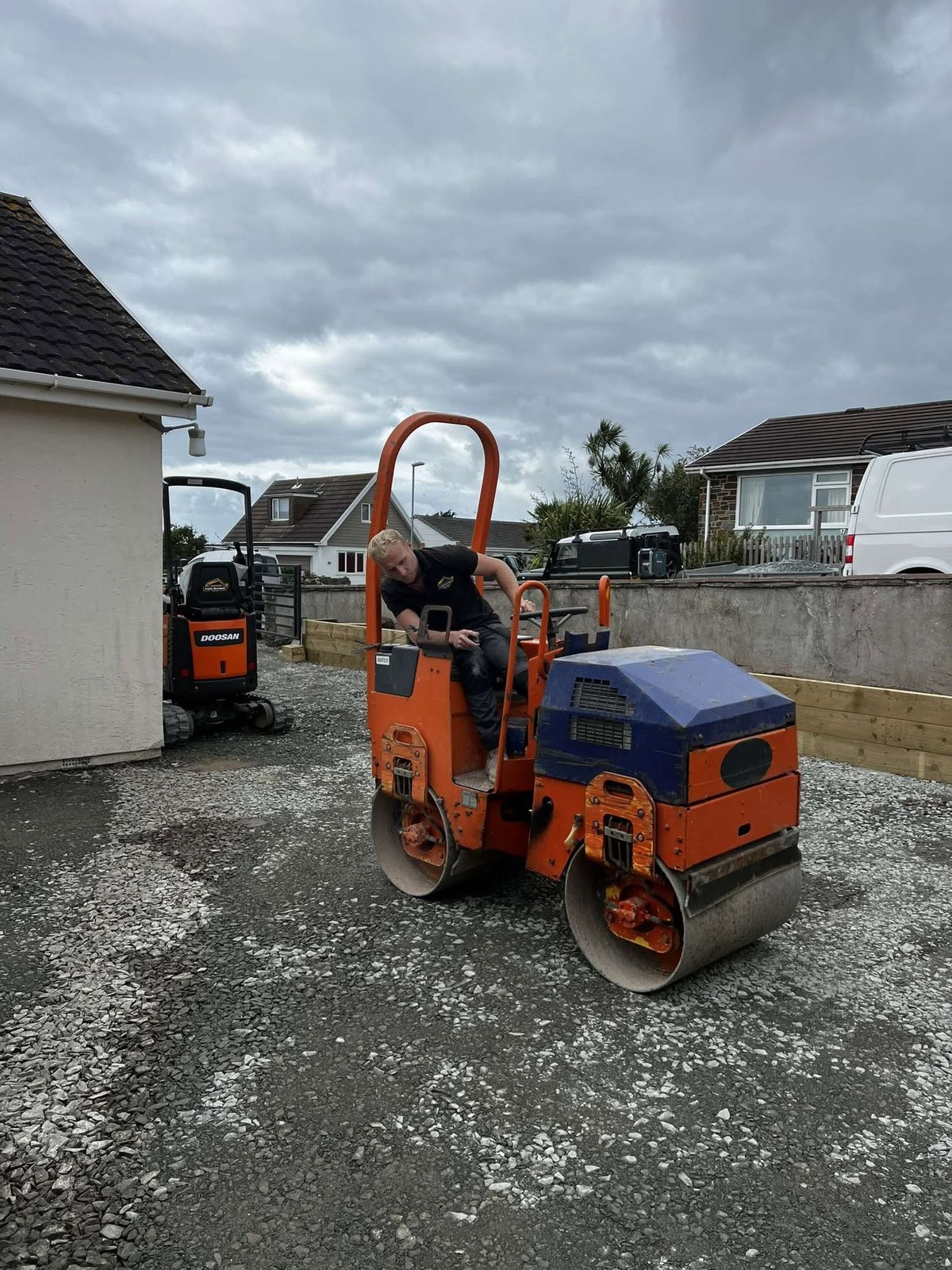 Orange road roller beside a residential surfacing job